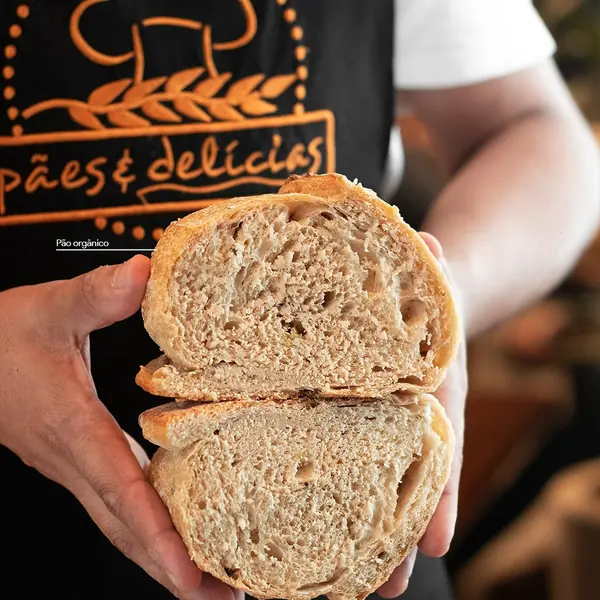 Pão de fabricação própria cortado ao meio nas mãos do padeiro